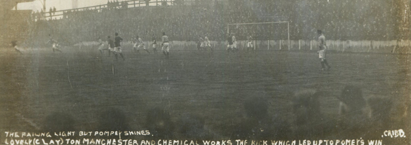 A photographic postcard of a football match in progress titled 'The Failing Light but Pompey Shines, Lovely (Clay)ton Manchester and Chemical Works the Kick which led up to Pompey's Win', published by Cribb