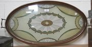 An Edwardian oval beadwork tea tray, the mahogany frame enclosing a glazed beadwork panel designed with a central fan patera, the sides with applied brass handles.