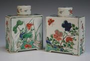 A pair of Chinese famille verte tea canisters and covers, Kangxi period, each rectangular body painted with flowers within green and black line borders, height approx 14.5cm (covers repaired and rubbed).