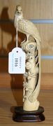 A Chinese ivory tusk carving, early 20th Century, of a bird perched on a blossoming branch, height approx 20.5cm, together with a hardwood stand.