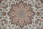 An Esfahan part silk rug, Central Persia, modern, the ivory field with a rose medallion supported by palmettes and flowering vines, within a beige palmette and curled leaf border, approx 246cm x 161cm.