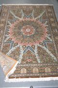 A Qum part silk rug, Central Persia, modern, the polychrome field with a multi-pointed star medallion and arched reserves, all filled with palmettes, flowering vines and arabesques, within a continuous arched niche border enclosing trees, plants and palmettes, approx 198cm x 138cm.