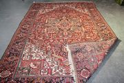 A Heriz carpet, North-west Persia, early/mid-20th Century, the claret field with a polychrome medallion, palmettes and leaves, within ivory spandrels and an ink blue flowerhead and leaf border, approx 347cm x 240cm.
