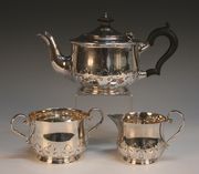 A George V silver three piece tea set, comprising teapot, milk jug and two handled sugar bowl, each of circular low bellied form with a cut-card work foliate band, London 1929 by C.E.