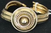 A Victorian gold bracelet, the front with a circular motif and bead to the centre within a ribbontwist surround, glazed with a locket compartment at the back, between serpentine linked sides.