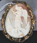 A Victorian oval shell cameo brooch, carved as the figure of an angel standing on clouds holding an arrow, within a pierced 'C' scroll mount.