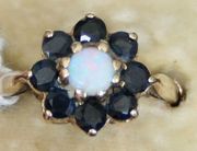 A 9ct gold, opal and sapphire stone cluster ring, claw set with the circular opal in a surround of eight circular cut diamonds.