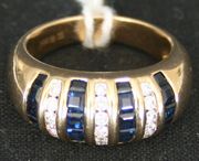 A sapphire and diamond ring, mounted with four rows of baguette sapphires alternating with three rows of circular cut diamonds in a bombé design, detailed '14k'.