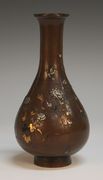 A Japanese inlaid and overlaid brown patinated bronze bottle vase, Meiji period, the body decorated in various metals with a design of blossoming branches and birds, signed to base, height approx 18.5cm.