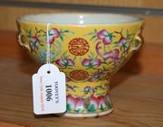 A Chinese famille rose yellow ground footed bowl, probably early 20th Century, of circular tapering form, the exterior polychrome enamelled with bats flying amongst peaches framing shou characters, height approx 10cm.