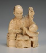 A Japanese carved ivory okimono figure group, Meiji period, in the form of a father reading to a child, signed, height approx 7.5cm (repaired arm).