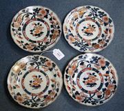 A set of four Japanese Imari porcelain plates, 18th Century, each decorated with a central circular floral panel within a rim border of chrysanthemum and foliage, heightened in gilt, diameter approx 21.5cm (minor faults).
