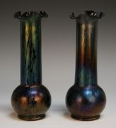 A pair of iridescent Loetz style glass vases, early 20th Century, each amethyst tinted body of spherical shape beneath an extended cylindrical neck with wavy rim, covered in a green/blue wash, unmarked, height approx 22cm.