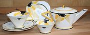 An Art Deco Shelley Vogue shape Sunray pattern part tea for two, decorated with an abstract sunburst in shades of yellow and black, comprising a teapot and cover, a teacup and two saucers, a sugar bowl and a small plate, printed and painted marks to bases.