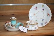 A Meissen porcelain chamberstick, circa 1900, the turquoise sconce moulded with a stiff leaf band flanked by a naturalistic handle on a circular saucer shaped base decorated with alternating panels filled with courting couples and flowers, heightened in gilt, cancelled crossed swords in underglaze blue to base, together with a Meissen porcelain inkwell, cover and stand decorated with scattered flowers (minor faults).