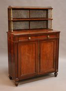 A Regency rosewood chiffonier, the two shelves with mirror panelled backs and a brass three-quarter gallery, trellis sides and reeded baluster columns, the base with single frieze drawer fitted with a writing surface inset with gilt tooled green leather revealing a well and flanked by compartments, the cupboard enclosed by a pair of panelled doors, on turned baluster legs, width approx 99cm.