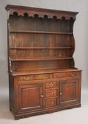 A George III oak dresser, the moulded pediment and fretwork frieze above three plate shelves, the base fitted with an arrangement of five drawers and two cupboards, on bracket feet, height approx 210cm, width approx 210cm (some alterations).
