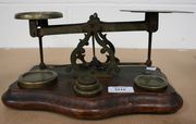 A set of brass postal scales and weights, on an oak serpentine fronted base.
