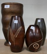 Four wooden vases, one of tapered ribbed shape, two with incised geometric decoration and one with foliate decoration.