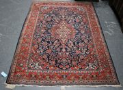 A Kashan rug, Central Persia, early/mid-20th Century, the dark blue field with a red foliate medallion and spandrels, supported by palmettes and flowering scrolls, within a red palmette and leaf border, approx 196cm x 133cm.