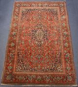 A pair of Kashan rugs, Central Persia, early 20th Century, each red field with a foliate lobed medallion and spandrels, all supported by flowering vines and palmettes, within complimentary borders, approx 202cm x 130cm.