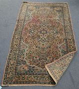 A Kerman rug, early 20th Century, the pink field with overall scrolling palmettes and flowerheads, within pale blue spandrels and a complimentary border, approx 180cm x 92cm.
