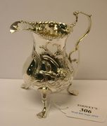 A George III silver cream jug, the baluster body chased with flowers and foliage, on tripod scroll trefoil feet, London 1771 by T.S.