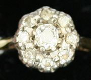 A gold and diamond set cluster ring, mounted with the principle cushion shaped diamond surrounded by eight further diamonds.