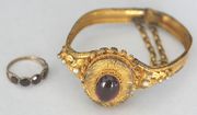 A Victorian carbuncle garnet and pearl set locket bracelet, the oval front mounted with a carbuncle garnet on an engraved ground within a ribbon twist border, between half pearl set scrolling sides, on a snap clasp, together with a garnet set five stone half hoop ring.