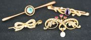 A gold, ruby and seed pearl set brooch in a scrolling design, mounted with three cushion shaped rubies above a single pearl drop, a gold, amethyst and seed pearl set bar brooch, and two further gem set brooches.