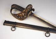 A Victorian Royal Military Academy presentation sword by Wilkinson, No. 23688, circa 1880, with curved single edged blade, length approx 84.5cm, etched with VR cypher and inscription 'Presented to Gentleman Cadet Matthew Nathan on obtaining his commission from the Royal Military Academy for his exemplary conduct whilst at the Institution', brass scrolled hilt with wire bound fishskin covered grip, in its steel scabbard.