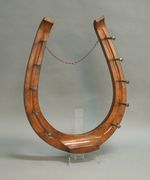 A late Victorian oak coat rack in the form of a horseshoe, fitted with ten brass nail shaped hooks, height approx 101cm.