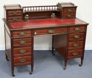 An Edwardian mahogany twin pedestal desk, the galleried back fitted with a shelf and drawers above a top inset with red gilt-tooled leather and an arrangement of nine drawers, on turned legs and castors, width approx 122cm.