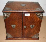 An Edwardian oak smoker's cabinet with plated mounts, the two doors enclosing a fitted interior of drawers, containing various smoking related items, including a meerschaum pipe.