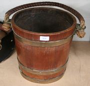 An early 20th Century mahogany and brass bound coopered bucket with leather-covered rope handle.