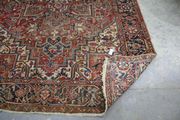 A Heriz carpet, North-west Persia, mid-20th Century, the red field with a bold flowerhead medallion supported by flowering vines, within a dark blue turtle palmette border, approx 330cm x 230cm.