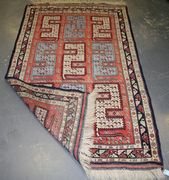 An Indian rug, mid-20th Century, the tangerine field with nine stylized 'S' motifs, within a charcoal border, approx 220cm x 125cm.
