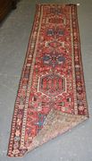 A Karajar runner, North-west Persia, early 20th Century, the red field with three hooked medallions, within a gul border, approx 285cm x 66cm.