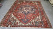 A Heriz carpet, North-west Persia, circa 1910, the terracotta field with a blue strapwork medallion supported by palmettes and flowering vines, within a complimentary border, approx 355cm x 288cm (faults).