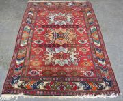 A Turkish rug, early/mid-20th Century, the red field with three shaped medallions supported by guls, within a blue continuous vine border, approx 212cm x 130cm.