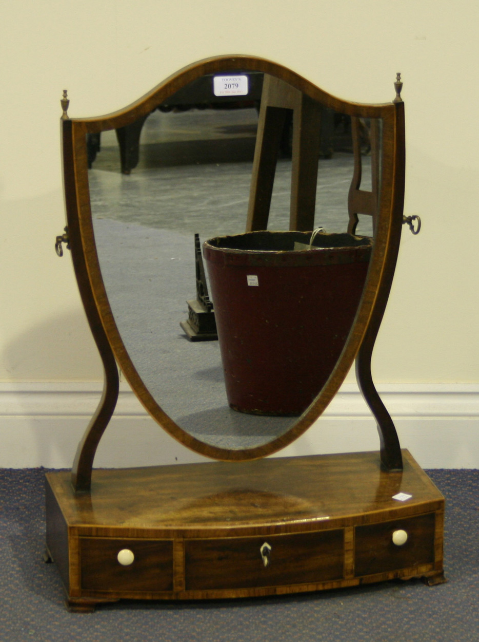 A George III mahogany shield shaped dressing table mirror, the bowfront ...