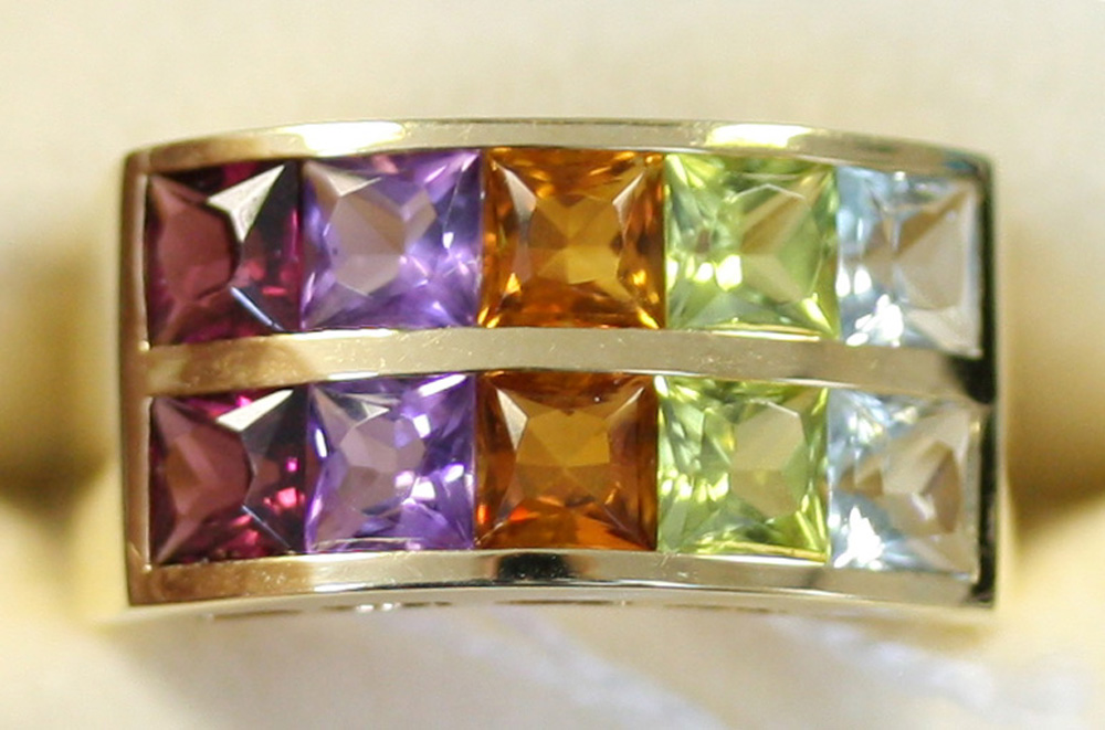 A gold, blue topaz, peridot, citrine, amethyst and garnet set ring in a ...