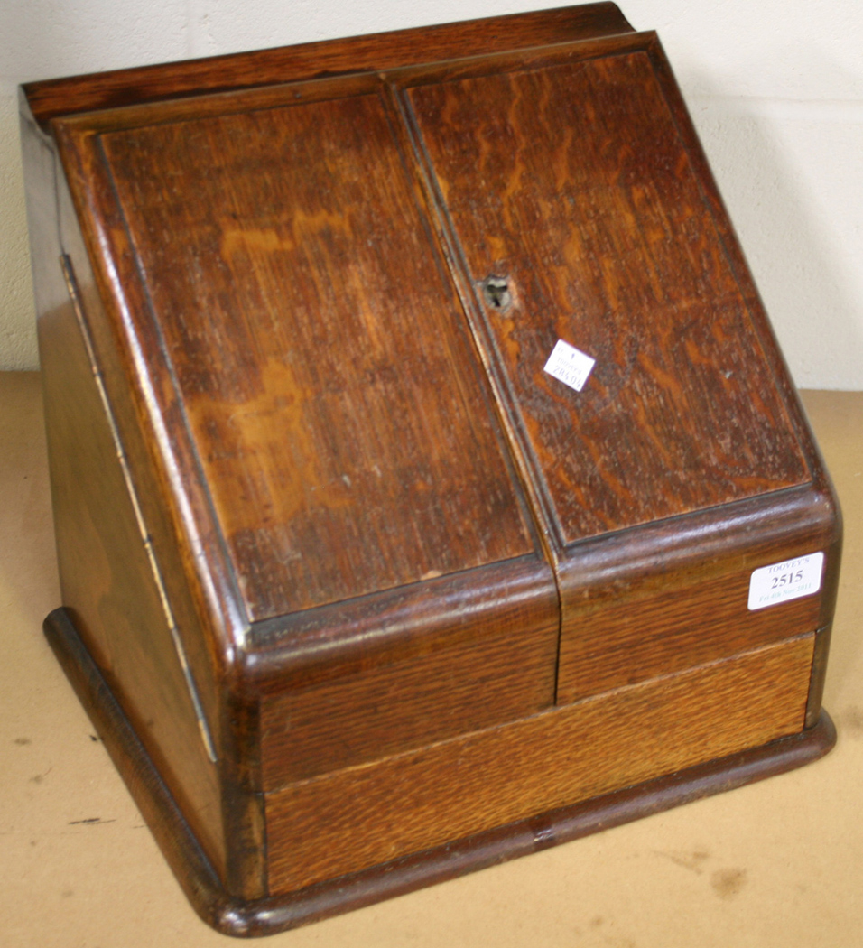 A late Victorian oak stationery box, the doublehinged sloping front