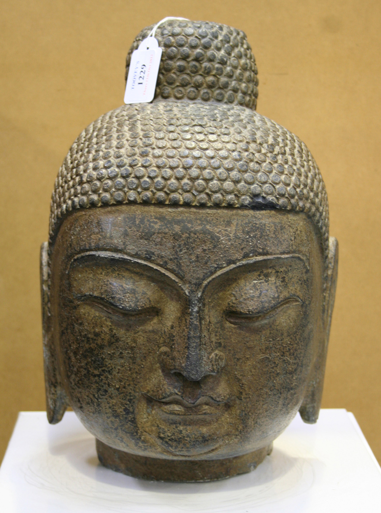 A Chinese carved stone Buddha's head, the hair arranged in tight curls and  rising to a domed un