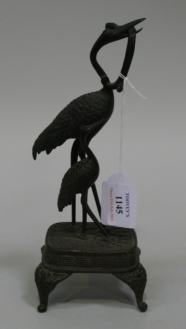 A Japanese bronze candlestick, Meiji period, modelled as two crane on a