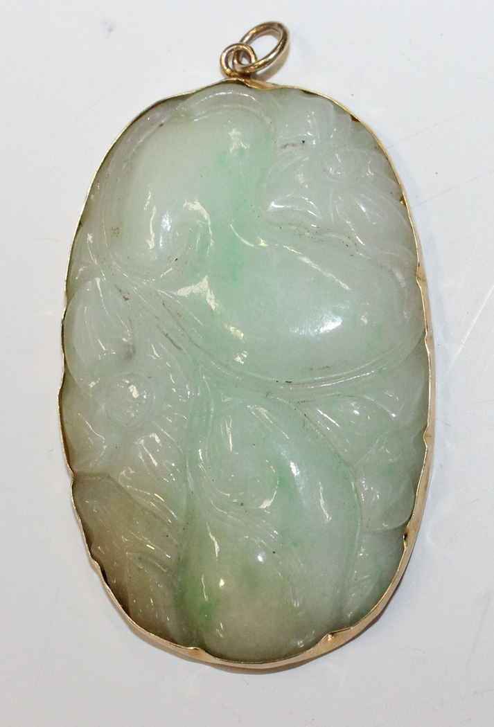 A Chinese gold mounted jadeite oval pendant, 20th Century, one side ...