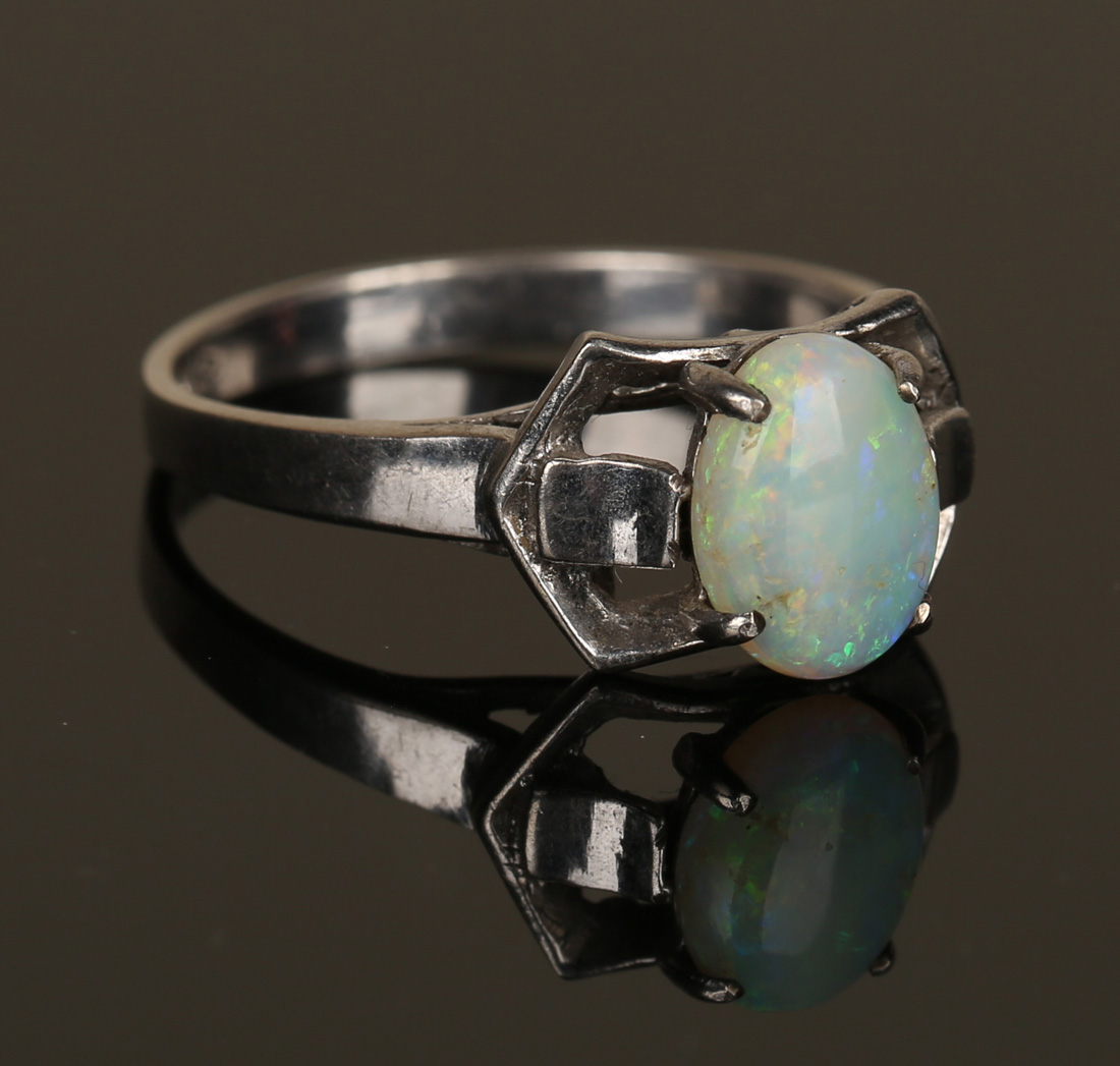 An opal single stone ring, claw set with an oval opal between pierced ...
