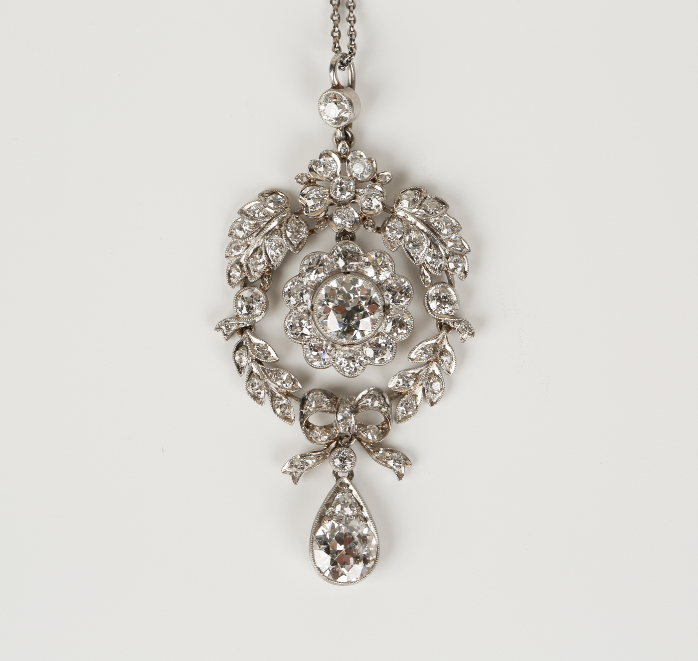 A diamond pendant, formed as a foliate wreath with a flowerhead ...