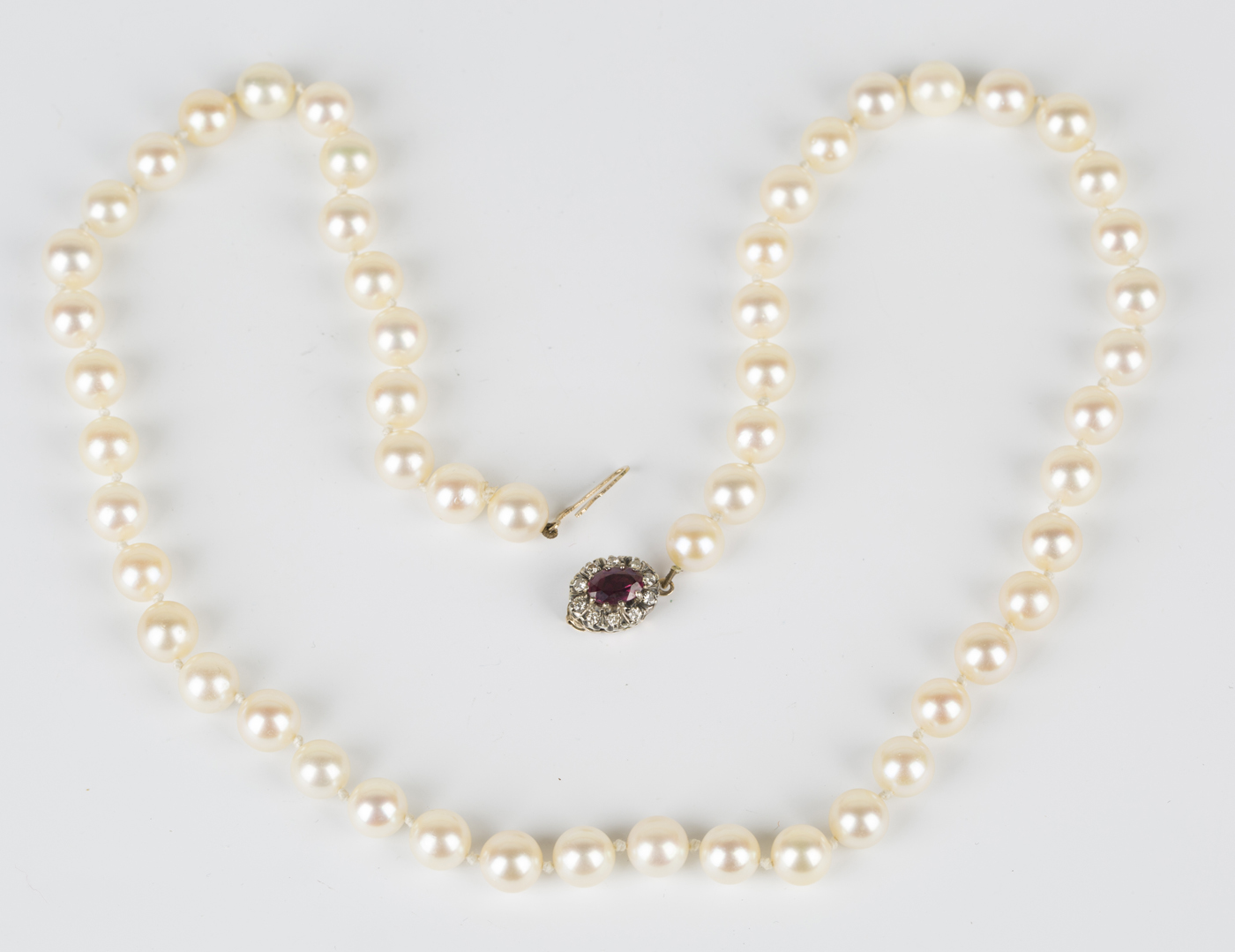 A single row necklace of uniform cultured pearls on a 9ct gold, ruby ...