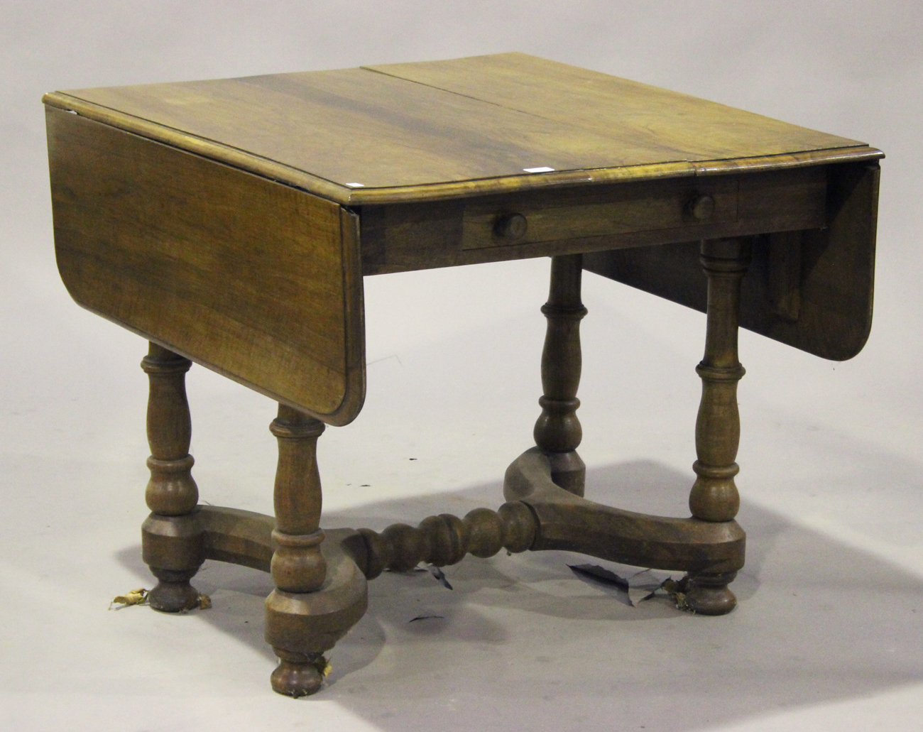 A Victorian walnut drop-flap dining table, raised on turned legs ...